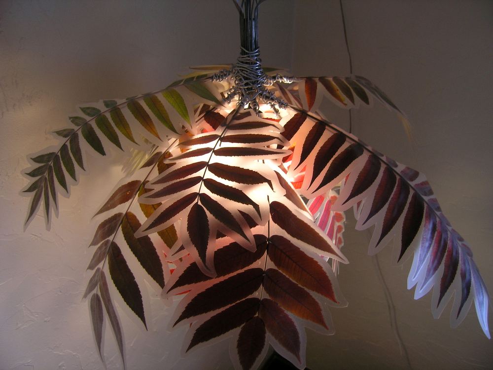A hanging light fixture built from copper-coloured metal fronds, lit from within.